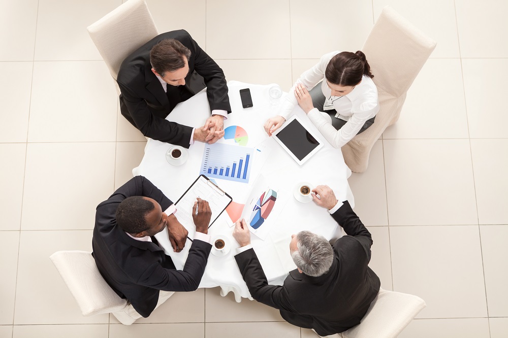 Business meeting in restaurant Team sitting behind desk, checking reports, talking. Top View