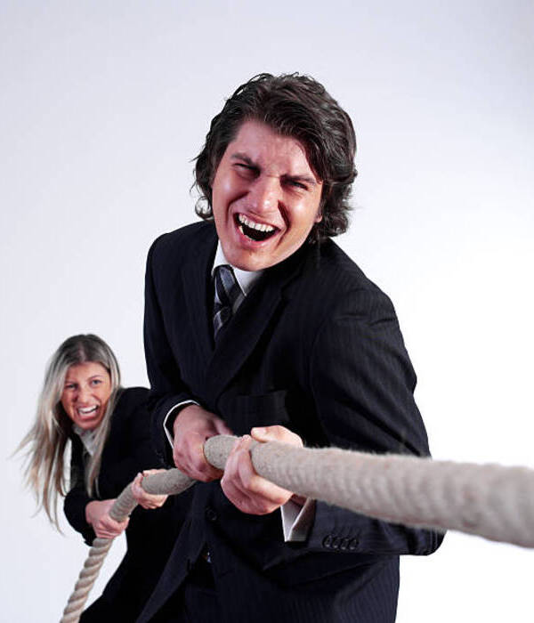Businessman and businesswoman playing tug of War in a office